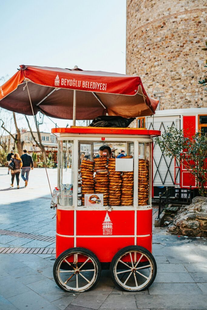 Small red cart with delicious bagels simit placed on street near building in Turkey on sunny summer day